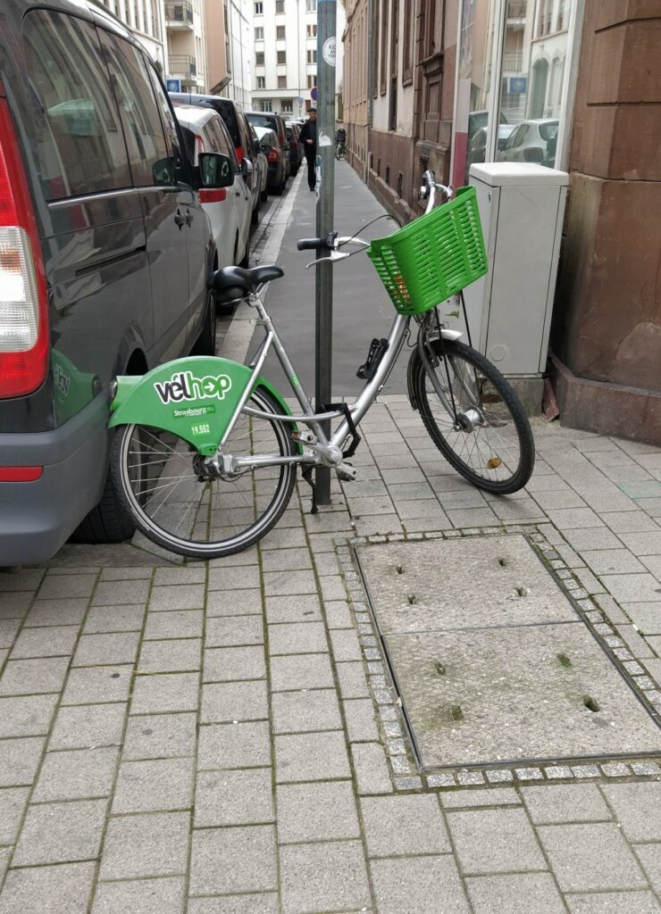 Un vélhop stationné à un poteau sur le trottoir bloque le passage des piétons