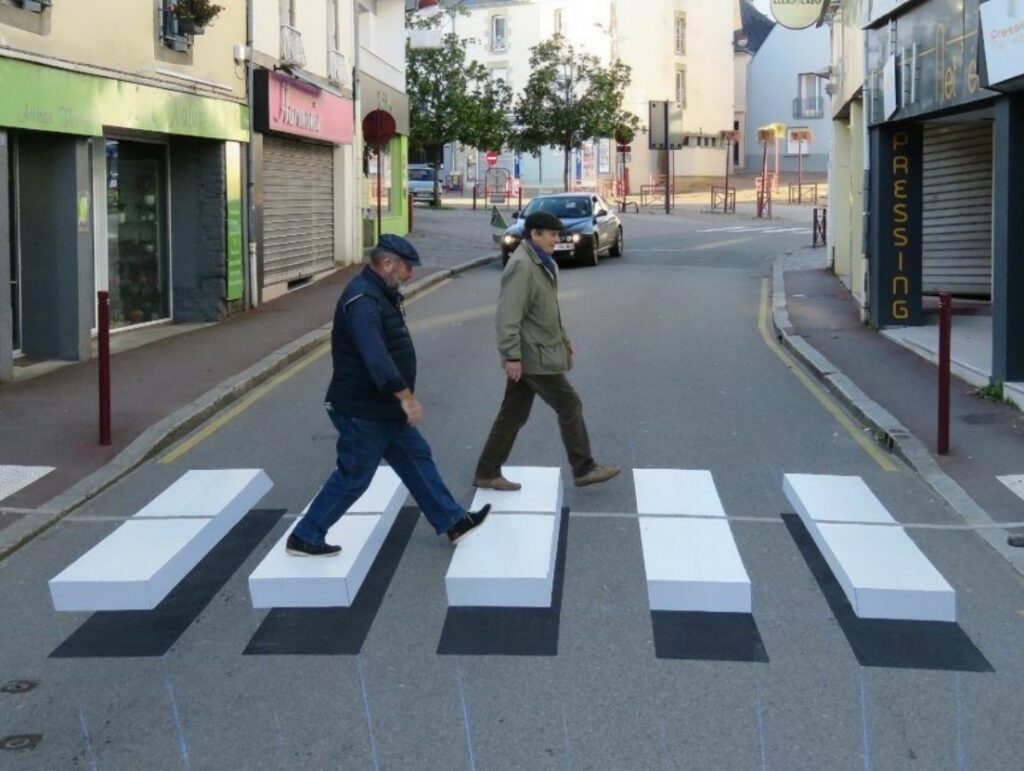 Deux piétons marchent sur un passage piéton trompe œil