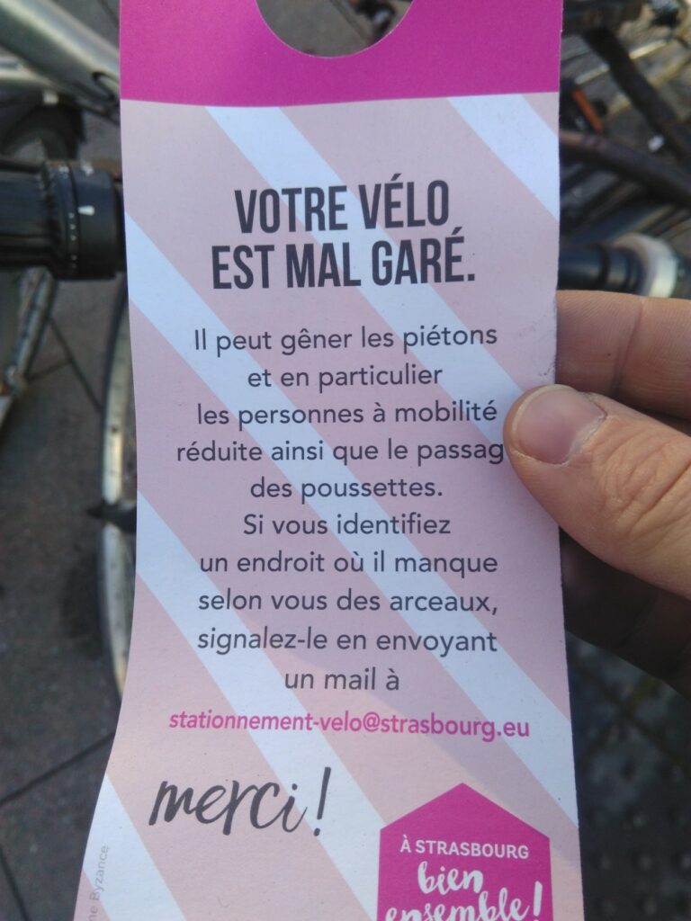 Un flyer type accroche porte avec écrit "Votre vélo est mal garé.
Il peut gêner les piétons et en particulier les personnes à mobilités réduite ainsi que le passage des poussettes. 
Si vous identifiez un endroit où il manque selon vous des arceaux, signalez-le en envoyant un mail à stationnement-velo@strasbourg.eu"