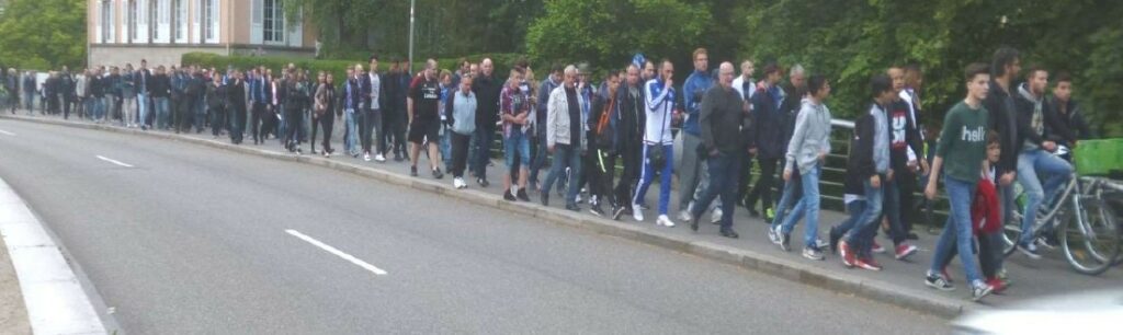 Longue file de piétons sur le trottoir se rendant au stade de la Meinau